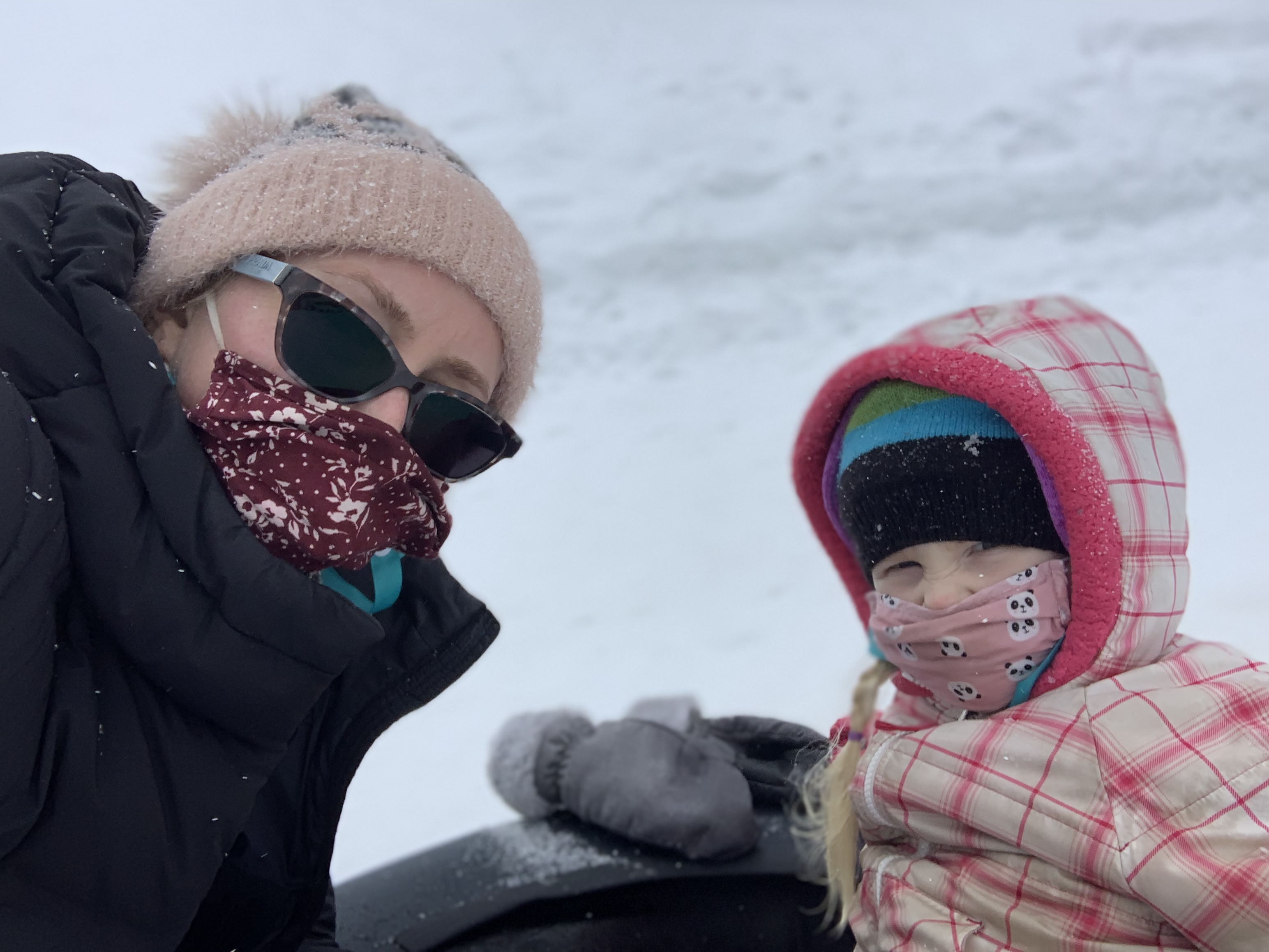 woman and child outside in the snow wearing masks